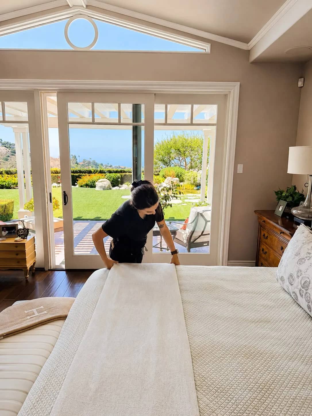 Gabby making the bed in a luxury Orange County home with garden view