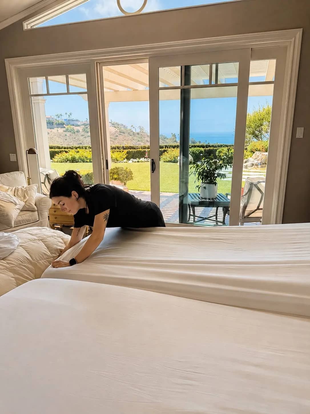 Gabby making the bed in an ocean-view Orange County master bedroom