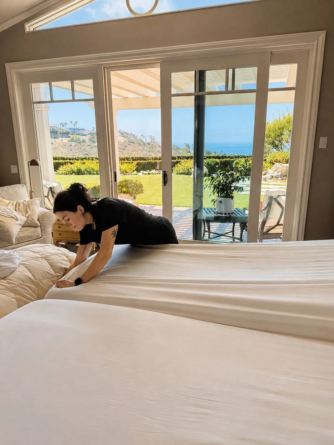 Gabby making the bed in an ocean-view Orange County master bedroom