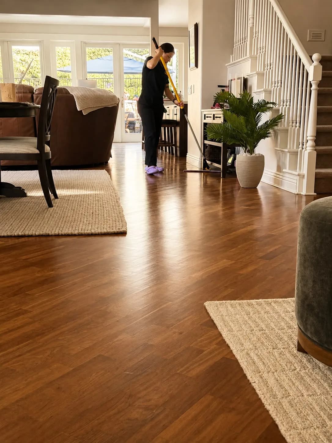 Gabby dust-mopping gleaming hardwood floors in an Orange County family home