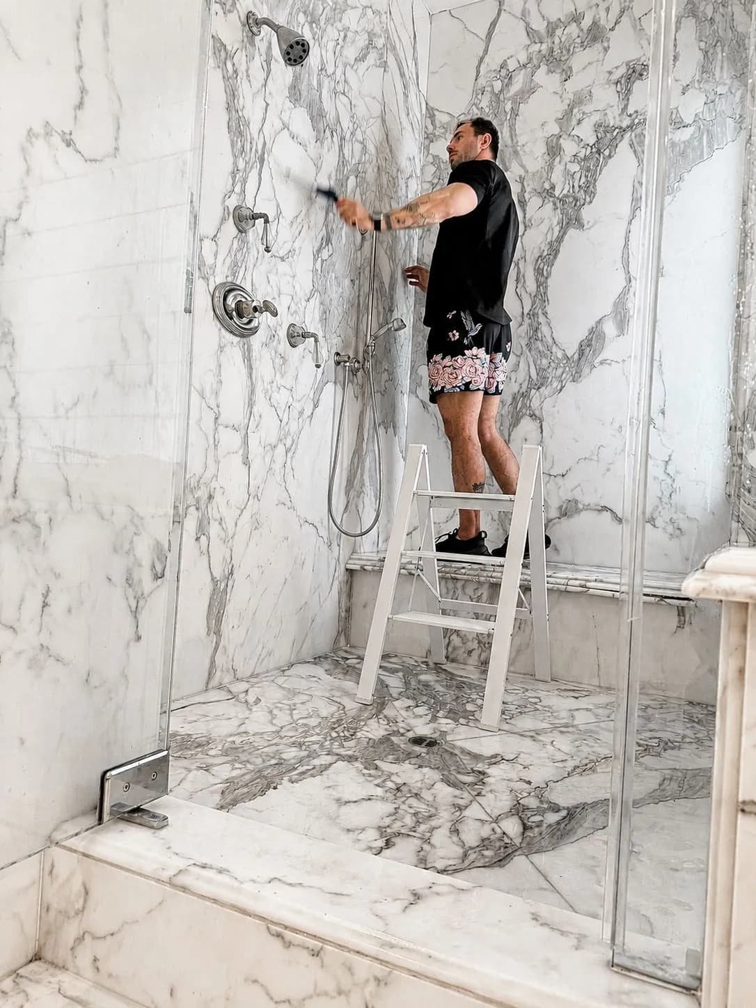 Paul deep-scrubbing a floor-to-ceiling marble walk-in shower in a Corona del Mar estate