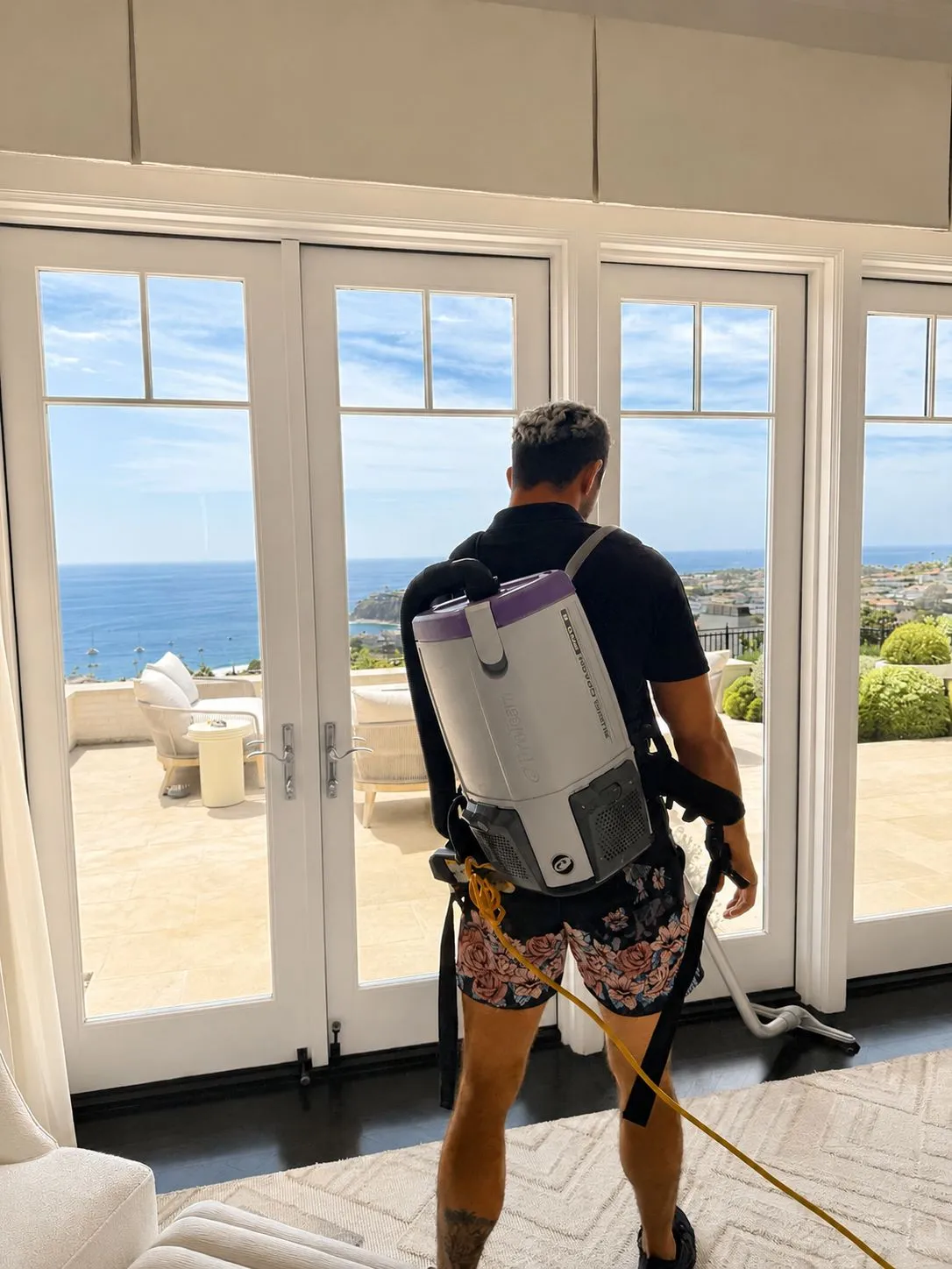 Paul backpack-vacuuming an ocean-view living room in a Laguna Beach estate