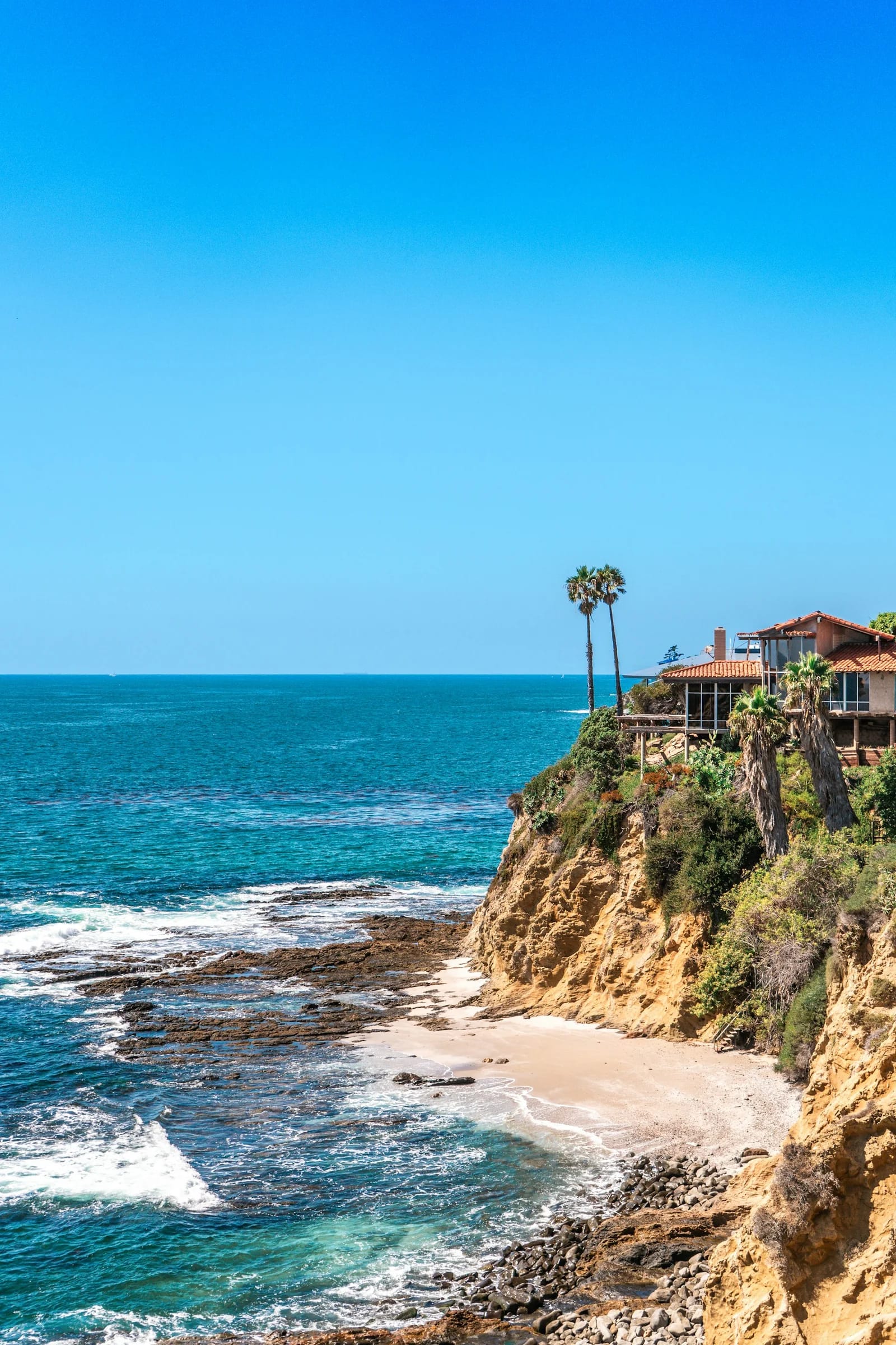 A terracotta-roofed coastal home and the shoreline at Crescent Bay, Laguna Beach