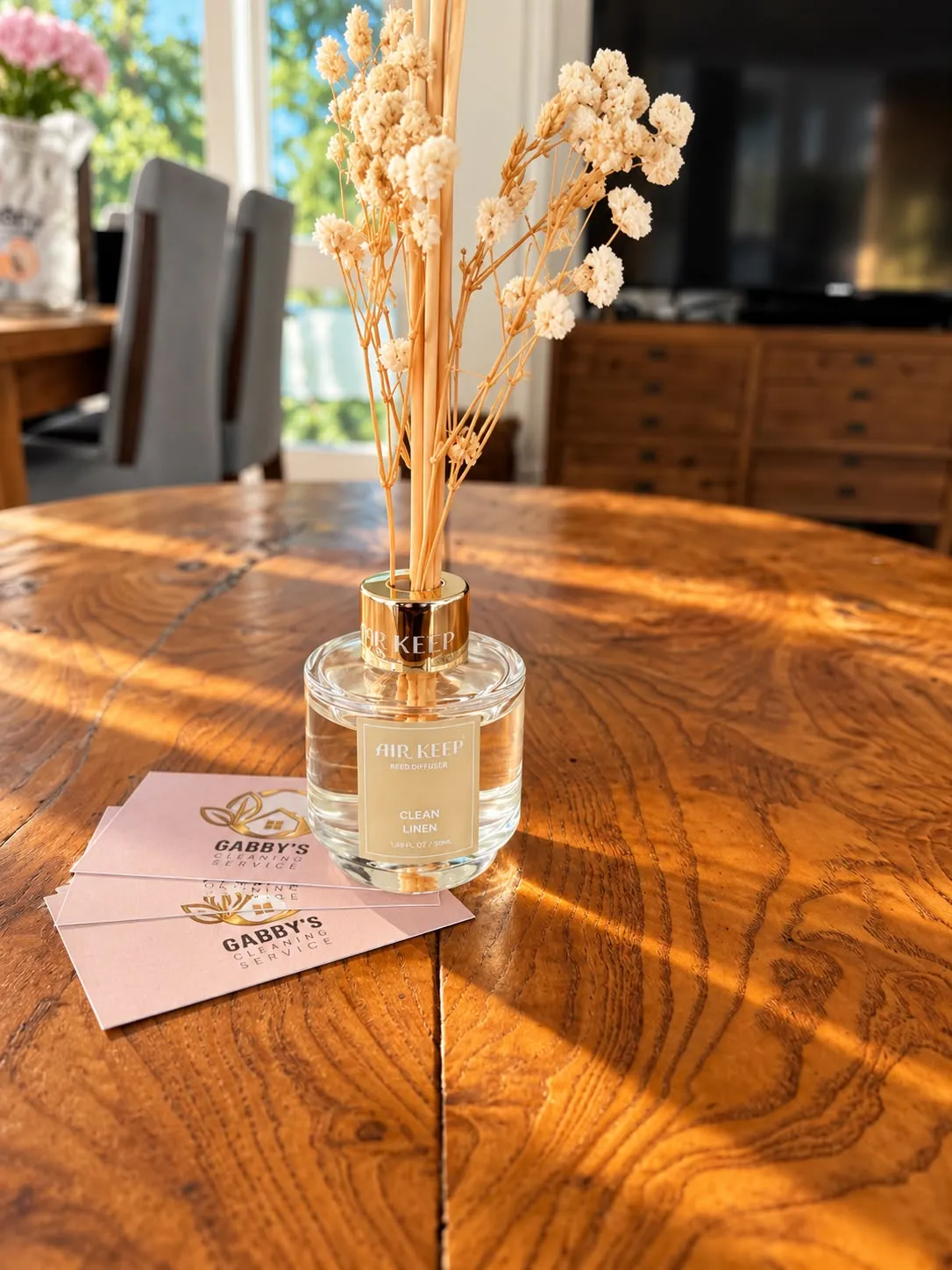 Gabby's Cleaning business cards beside a reed diffuser on a sunlit wood table